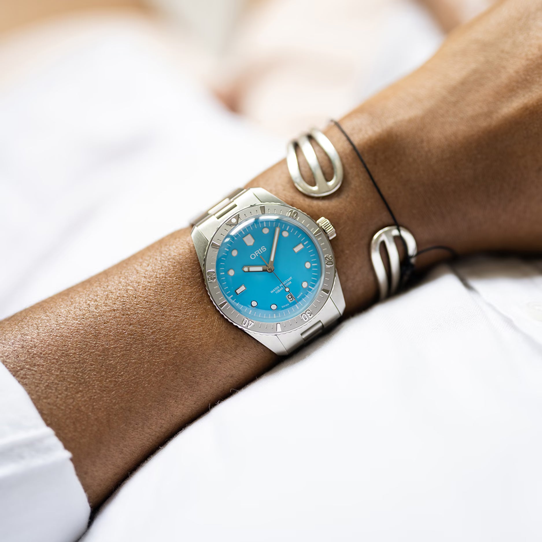 Oris Divers Sixty-Five Cotton Candy Unisex 01 733 7771 4055-07 8 19 18 horloge 38mm met turquoise wijzerplaat en roestvrijstalen band, gedragen om een pols. Luxe Swiss Made heren horloge voor dames en heren.