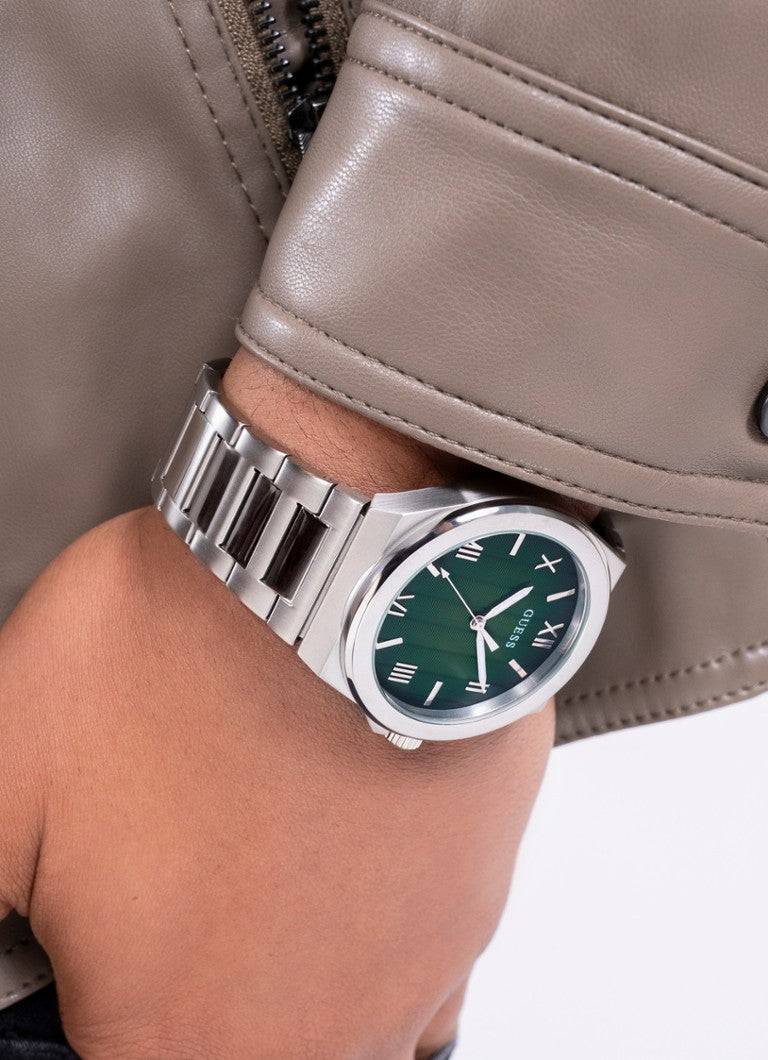 Guess Dress Herenhorloge - Groen 44mm met groene sunburst wijzerplaat en zilverkleurige band, gedragen bij beige leren jas. KW & 3 ATM.