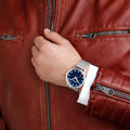 Mondaine Classic Spoorweg Horloge 40mm M660.30360.40SBJ heren horloge met blauwe wijzerplaat en mesh band, gedragen bij roodleren jas. Swiss Made design.