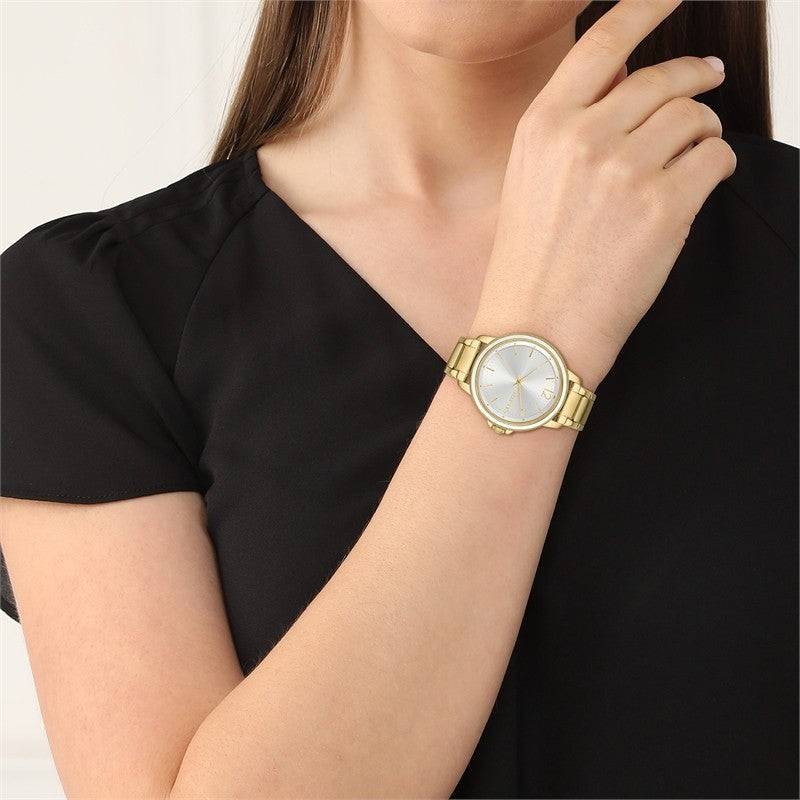 Lacoste dameshorloge - LC2001221 met goudkleurige band en witte wijzerplaat, elegant gedragen bij zwarte blouse. Tijdloos accessoire voor dames.