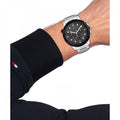 Tommy Hilfiger TH1792106 Troy Herenhorloge 46mm met zilverkleurige schakelband en zwarte wijzerplaat, gedragen om pols van man. Stijlvol accessoire voor modebewuste heren.