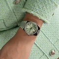 Gc Classic Dameshorloge 34mm - Z38001L9MF met mintgroene wijzerplaat en zilverkleurige band, gedragen bij een mintgroene jas. Elegant Swiss Made dameshorloge.