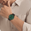 Calvin Klein CK25200440 Gauge herenhorloge 44mm met groene wijzerplaat en zwarte mesh band, gedragen door man in beige overhemd. Stijlvol quartz horloge voor heren.
