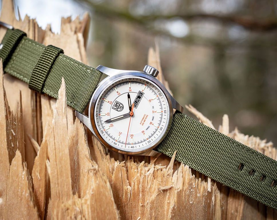 Luminox xl 1907 nf Atacama Field Automatic Herenhorloge 45mm met wit wijzerplaat en groene nylon band, outdoor stijl op gebroken hout. Swiss Made herenhorloge voor avontuurlijke stijl.