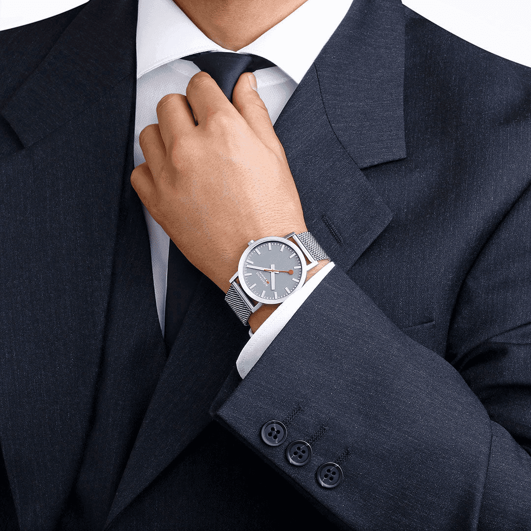Mondaine Classic Spoorweg Horloge 40mm M660.30360.80SBJ gedragen door man in donker pak. Swiss Made heren horloge met minimalistisch design en metalen mesh band.