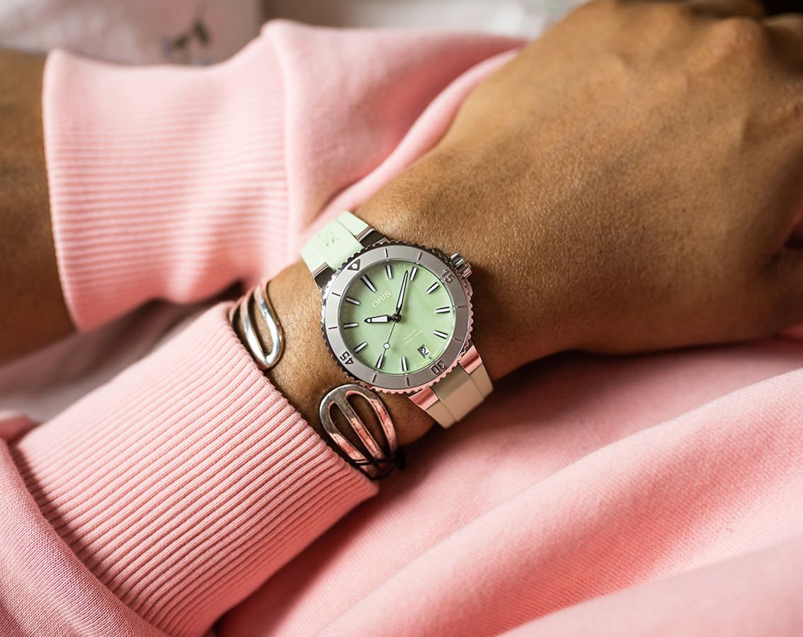 Oris Dameshorloge 36,5 mm met mintgroene wijzerplaat en witte rubberen band, gedragen om de pols. Stijlvolle tijdwaarneming voor elke gelegenheid.